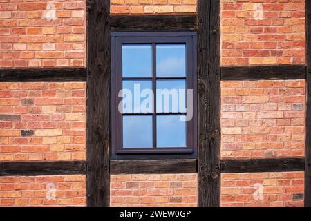 A window in the frame wall of a red brick and wooden building Stock Photo
