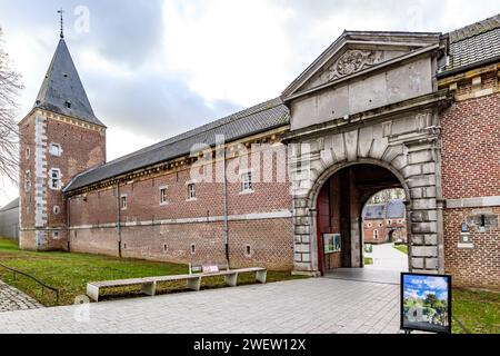 Majestic old Alden Biesen castle from 16th century, arched entrance between brick walls, path to outer courtyard in background, cloudy day in Bilzen, Stock Photo