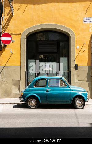 Blue Fiat 500 parked in front of an old palazzo with yellow facade, in the Oltrarno district of Florence, Tuscany, Italy Stock Photo