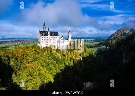 The castle Neuschwanstein, surrounded by colourful trees, seen from the bridge Marienbrücke in autumn. Stock Photo