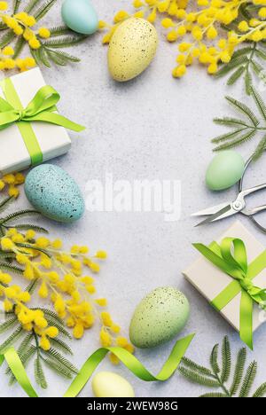 Mimosa branch, Easter eggs and gift boxes  on gray concrete background.  Beautiful Easter spring background with place for text. Stock Photo
