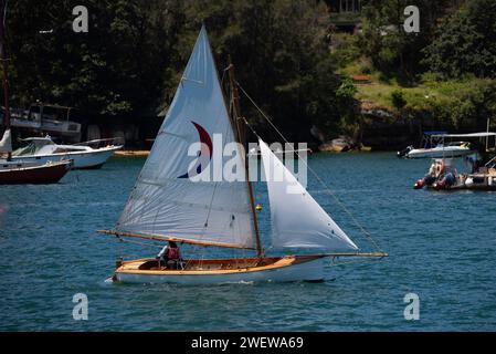 An open wooden sailing boat with a gaff rigged mainsail and jib sail set, sailing on Sydney Harbour in Australia on a sunny day Stock Photo