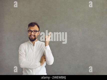 Happy man has an idea and points his finger up standing on a grey copy space background Stock Photo