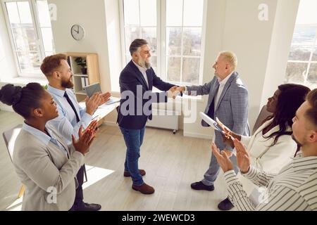 Business people standing in office making deal on meeting. Two mature men shaking hands. Stock Photo