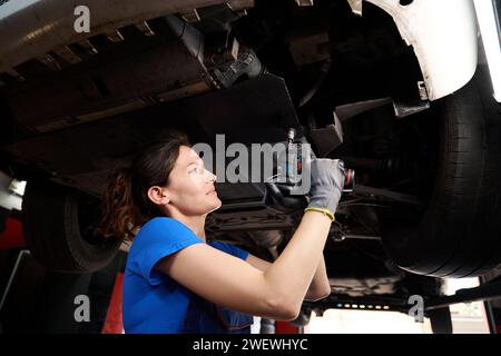 Auto mechanic works under a car raised on special lift Stock Photo