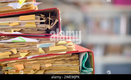 messy file folders,red tape, bureaucracy,aministration,business concept,isolated on blurred office bookshelf backgound Stock Photo