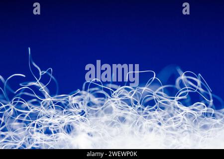 Extreme macro of polyester stable fiber on blue background. Selective focus, shallow depth of field. Abstract dreamy background Stock Photo