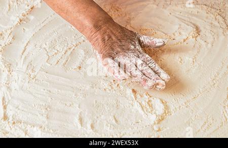 Dough on white powder covered table. Hand flour. Hands baker with flour in kitchen. Hands woman covered in flours. Women's hands, flour and dough Stock Photo