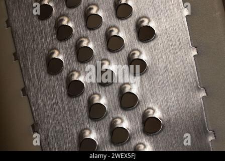 lose up or macro photo of the sharp metal on a Cheese Grater, that is used to shred Cheese. Stock Photo