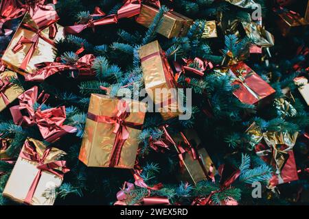 A Christmas tree adorned with golden gift boxes and red ribbons Stock Photo