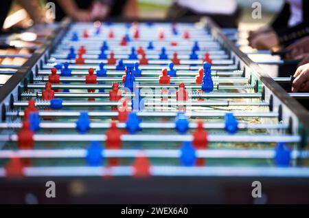 Foosball table, competitive and leisure with people playing a game outdoor at a music festival together. Party, event or social gathering with friends Stock Photo