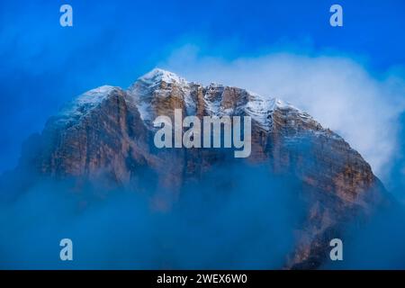 The snow-covered summit of Mount Tofana di Rozes rises out of the clouds, seen from the rock formation Cinque Torri. Cortina d Ampezzo Veneto Italy FB Stock Photo
