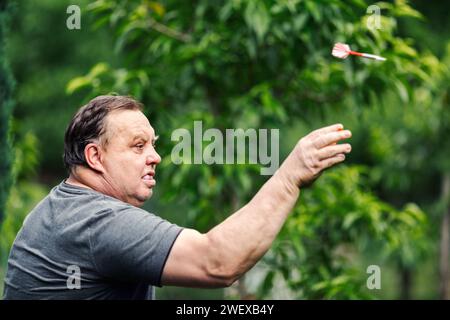 Man playing a game of darts. He needs concentration and perfection to win Stock Photo