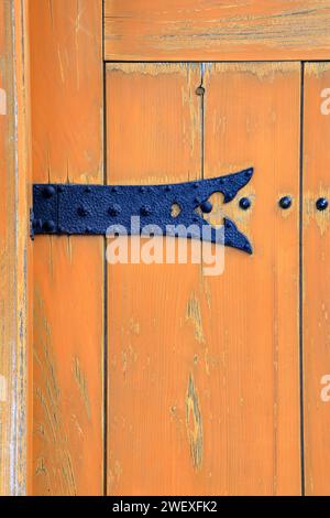 Vintage door hinge. Rusty metal hinge on yellow wood door. Stock Photo