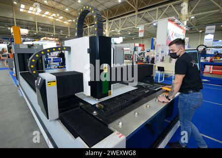 Laser machine cutting metal sheet, man worker controlling. November 17, 2021. Kyiv, Ukraine Stock Photo