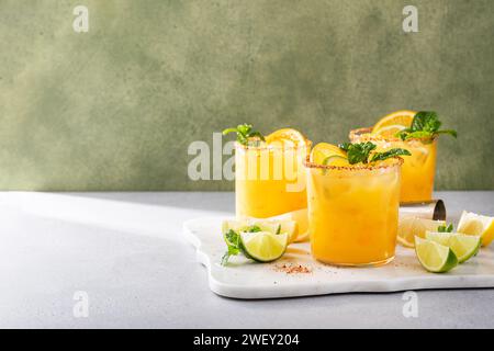 Spicy orange margarita with lime and orange slices garnished with mint and a spicy rim Stock Photo