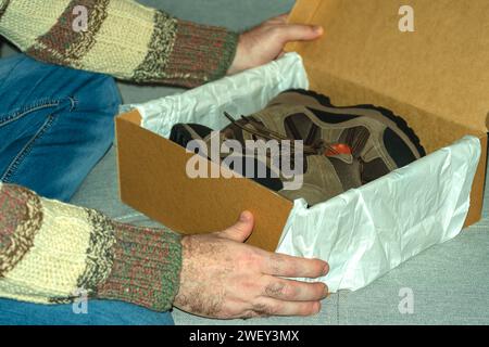 close-up. The man holds box with shoes in hands. Concept of buying, trying on shoes and boots. Stock Photo