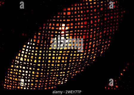 The light of a candle is visible through a fine straw mesh in the dark, background, mesh for background Stock Photo
