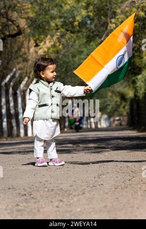 young kid waving the indian tricolor national flag at day from flat angle Stock Photo