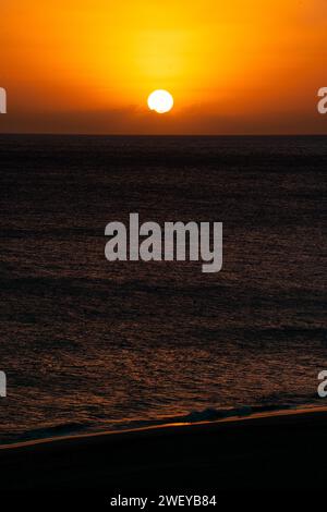 Vibrant sunset over the ocean with a breathtaking orange sky and scattered clouds Stock Photo
