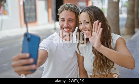A happy couple takes a selfie on a sunny urban street, showcasing love and connection in an everyday cityscape. Stock Photo