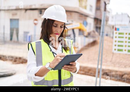 Young beautiful hispanic woman architect drawing on touchpad with relaxed expression at street Stock Photo