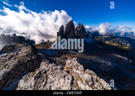 The north faces of the Tre Cime di Lavaredo rock formation in the Tre Cime National Park, surrounded by clouds, seen from Monte Paterno summit. Cortin Stock Photo