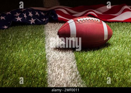 A football and American flag on grass field with stripe in dramatic light Stock Photo