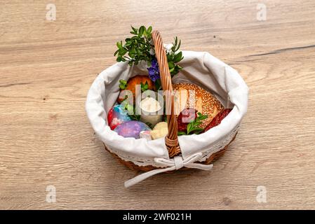 A wicker Easter basket filled with food standing on a table, decorated with boxwood and catkins. Stock Photo