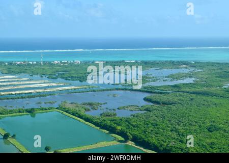 An aerial view of south San Pedro, Ambergris Caye, Belize. The barrier reef can be seen in the background with white waves crashing into it. Stock Photo