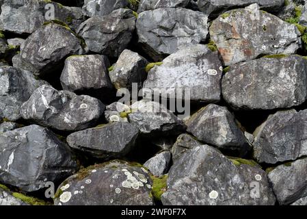 A rock retaining wall with lichen and moss growing on the rocks Stock Photo