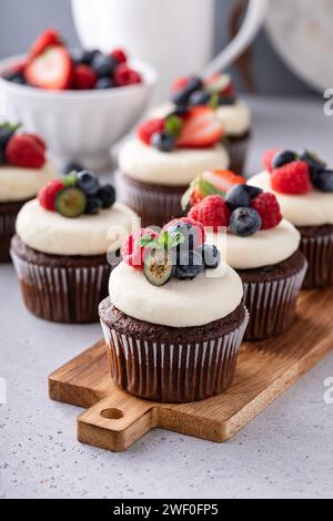 Chocolate cupcakes with vanilla frosting and fresh berries on top Stock Photo