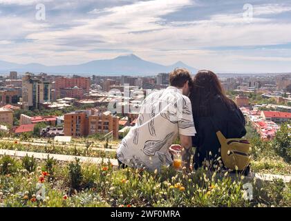 Love couple sitting high with panoramic view on Yerevan city and Ararat from Armenian cascade Stock Photo