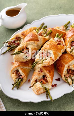 Asparagus appetizers wrapped in puff pastry with melted cheese and topped with bacon Stock Photo
