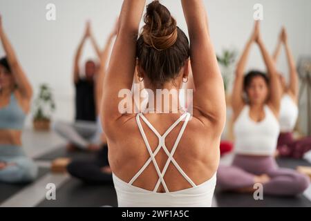 Group diverse fitness young people practicing yoga exercises indoors. Concentrated meditating. Stock Photo