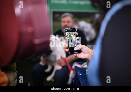 New York, USA. 27th Jan, 2024. A woman photographs a sleepy British Bulldog named 'QT' as he sits on his owner's lap Ken McKenna at the AKC 'Meet the Breeds' event at the Jacob Javits Center, New York, NY, January 27, 2024.(Photo by Anthony Behar/Sipa USA) Credit: Sipa USA/Alamy Live News Stock Photo