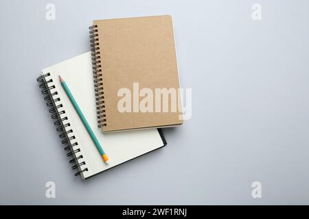 Notebooks and pencil on light grey background, top view. Space for text Stock Photo
