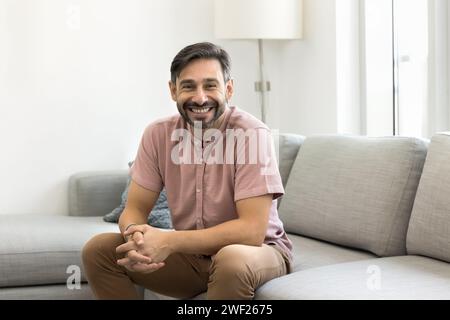 Happy handsome middle aged man sitting on comfortable sofa Stock Photo