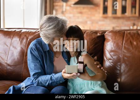 Excited preteen latina girl get gift greeting kiss from grandma Stock Photo
