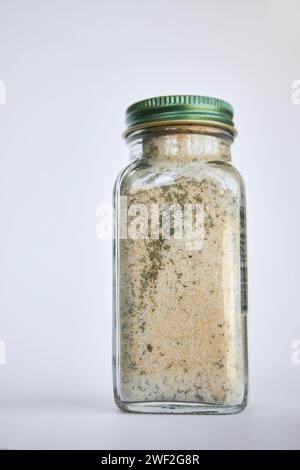 Glass jar with loose dried mixture close-up. Using reusable, recyclable Eco-friendly packaging in everyday life. Organic Seasoning Blend mix. Gray background.  Stock Photo