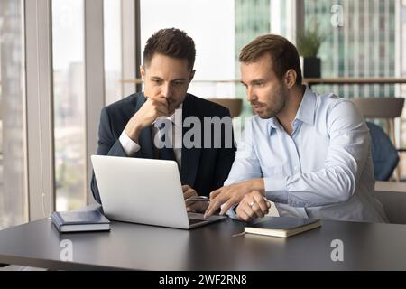 Two serious confident business colleagues men working at laptop Stock Photo