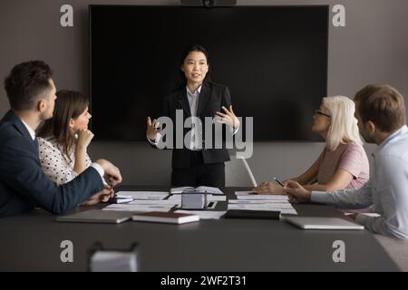 Engaged young Asian project manager presenting startup to coworkers Stock Photo