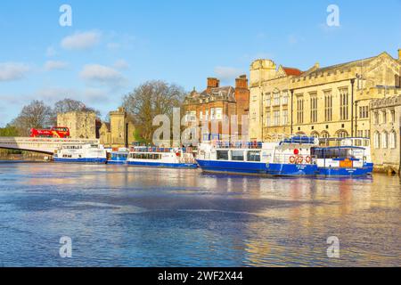 York, England. January 26 2024. River boats on the River Ouse in the historic city of York with red double decker bus crossing Lendal Bridge. Horizont Stock Photo