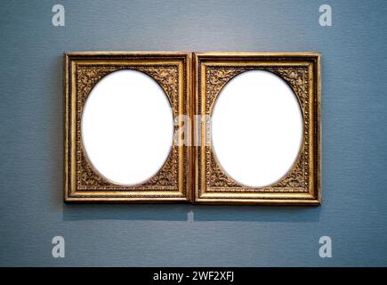 Mockup two white oval blank space in classic gold wooden square louise style frames hanging isolated on light blue luxury background. Empty  oval spac Stock Photo