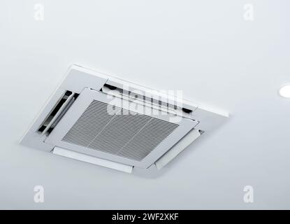 Ceiling mounted cassette type air conditioner decoration near ceiling lights on white building interior. Ceiling type of air conditioning unit with ve Stock Photo