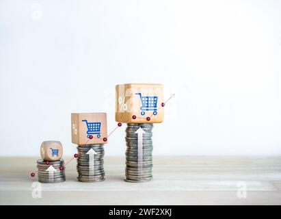 Shopping cart icon and percentage symbol on wood cube blocks on coin stacks as growth graph steps with rise arrows on white background. Business marke Stock Photo