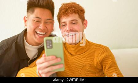 Gay couple sitting on the sofa using a mobile phone Stock Photo