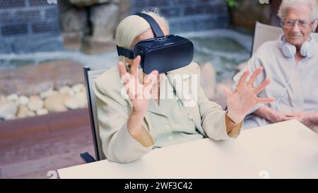 Senior woman gesturing while using virtual reality goggle in geriatric Stock Photo