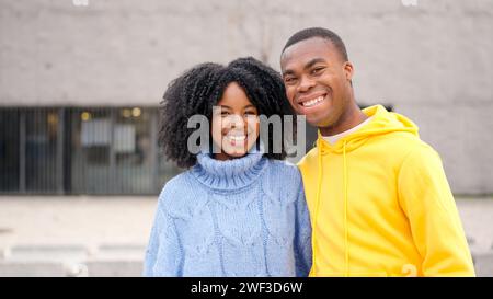 African couple smiling at camera standing in the street Stock Photo