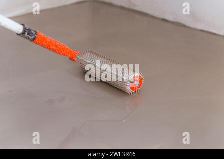 Needle roller for self-leveling floors. Leveling the floors with a cement mixture. Stock Photo